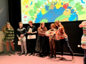 Our five animators being presented with a gift in front of the big screen at the animation celebration in Sheffield Hallam University